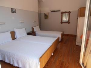 Habitación de hotel con 2 camas con sábanas blancas en Hotel Bretagne, en Loutraki
