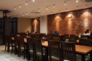 uma sala de jantar com mesas e cadeiras e uma parede de tijolos em Ahyu Hotel em Kuala Lumpur