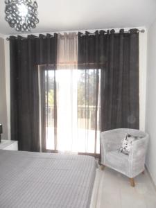 ein Schlafzimmer mit einem Bett, einem Stuhl und einem Fenster in der Unterkunft Lovely 1 Bed Apartment - Vista das Ondas in Albufeira