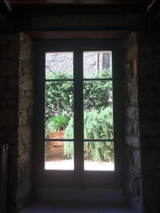a window in a brick wall looking out at a plant at Le Antiche Mura in Semproniano