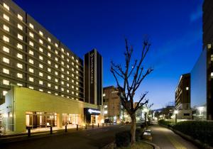 ein Gebäude mit einem Baum in der Mitte einer Straße in der Unterkunft Daiwa Roynet Hotel Sakai Higashi in Sakai