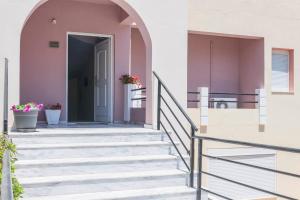 eine Treppe, die zu einem Haus mit rosa Wänden führt in der Unterkunft Nikos Apartments in Agia Marina