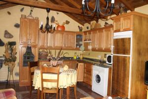 a kitchen with wooden cabinets and a table with a white dishwasher at Casa Rural El Rincón de Antonia in Agulo