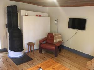 a living room with a fireplace and a chair and a tv at Hyttsnåret in Östra Löa