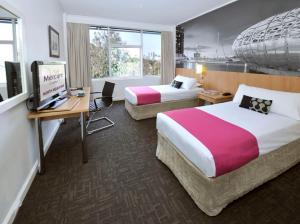 a hotel room with two beds and a desk at Mercure North Melbourne in Melbourne