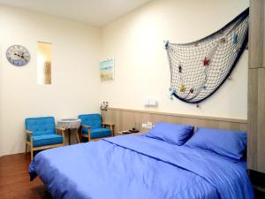 um quarto com uma cama e duas cadeiras azuis em Ji Shih Life Style Hotel em Tainan