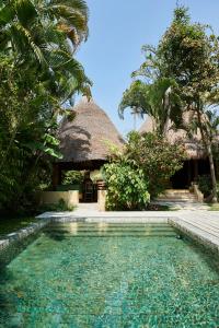 a resort with a swimming pool in front of a building at The Island Houses Seminyak in Seminyak