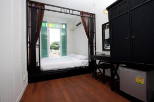 1 dormitorio con cama, escritorio y espejo en 99 Oldtown Boutique Guesthouse SHA EXTRA PLUS, en Phuket