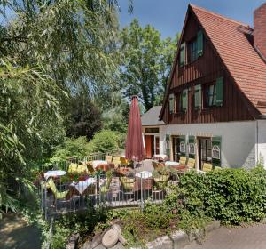 ein Haus mit Tischen, Stühlen und einem Sonnenschirm in der Unterkunft Hotel Restaurant Lohmühle in Bayreuth