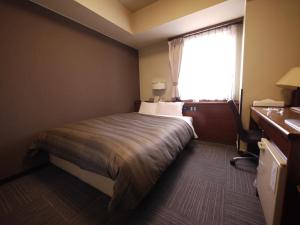 a hotel room with a bed and a window at Hotel Route-Inn Daiichi Nagano in Nagano