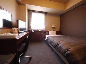 a hotel room with a bed and a desk with a computer at Hotel Route-Inn Daiichi Nagano in Nagano
