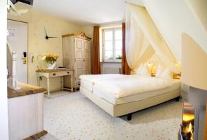 a bedroom with a canopy bed and a desk at Hotel Restaurant Lohmühle in Bayreuth