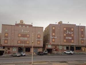 dos grandes edificios con coches estacionados en un estacionamiento en Bzul For Furnished Apartments, en Riad