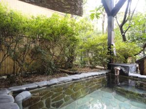 a swimming pool in a garden with a fountain at Yoshimatsu in Hakone