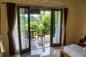Schlafzimmer mit einer Glasschiebetür, die auf einen Balkon führt in der Unterkunft Pondok Bali in Ubud