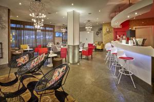 a restaurant with chairs and tables and a bar at Kyriad Prestige Lyon Est - Saint Priest Eurexpo Hotel and SPA in Saint-Priest