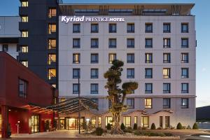 un hôtel avec un palmier en face d'un bâtiment dans l'établissement Kyriad Prestige Lyon Est - Saint Priest Eurexpo Hotel and SPA, à Saint-Priest