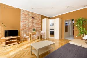 a living room with a tv and a brick wall at East Station Studios - Baross Home 1 & 2 in Budapest