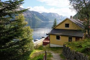 a yellow house on the side of a lake at Flørli 4444 Hostel in Fløyrli