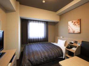 a hotel room with a bed and a window at Hotel Route Inn Toyama Inter in Toyama