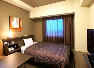 a hotel room with a bed and a window at Hotel Route Inn Toyama Inter in Toyama