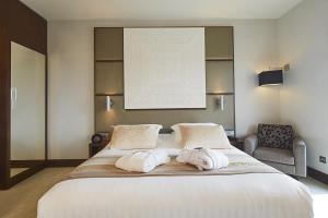 1 dormitorio con 1 cama grande y toallas. en Kyriad Prestige Lyon Est - Saint Priest Eurexpo Hotel and SPA, en Saint-Priest
