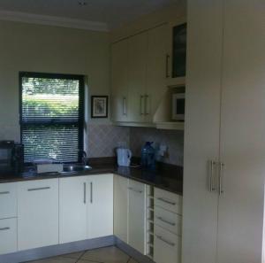a kitchen with white cabinets and a window at Longmere Cottages in White River