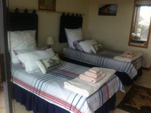 two twin beds in a room with towels on them at Longmere Cottages in White River