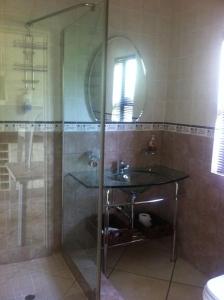 a bathroom with a glass shower and a sink at Longmere Cottages in White River