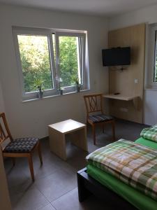 エッセンにあるBergcafè - Hotel Kammannのベッド2台、椅子2脚、窓2つが備わる客室です。