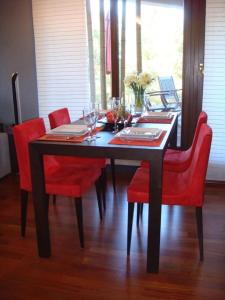 a dining room table with red chairs and a table with wine glasses at Apartament Hong Kong in Jurata