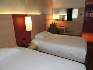 a hotel room with two beds and a desk at Cascina Scova Resort in Pavia