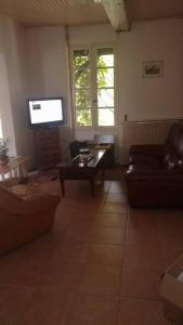 sala de estar con sofá y TV de pantalla plana en B&B Les Quatre Vents, en Montpon-Ménestérol