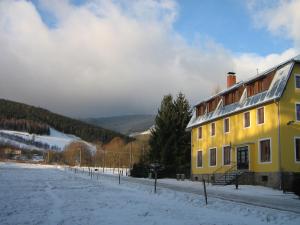 a yellow house in the snow next to a field at Kralicka Chata in Staré Město