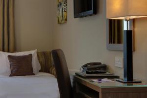 a bed room with a desk and a lamp at Best Western Pontypool Metro Hotel in Pontypool