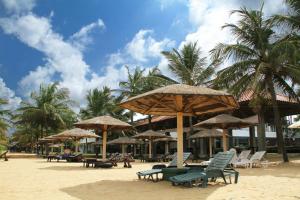 a group of chairs and umbrellas on a beach at Goldi Sands Hotel in Negombo