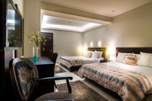 カストリアにあるPansion Zafeiriouのベッド2台、デスク、椅子が備わるホテルルームです。