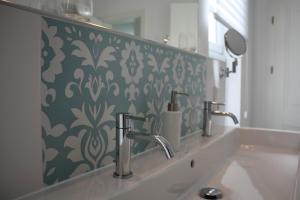 a bathroom sink with two faucets and a green and white wallpaper at Hotel Altes Dichterhaus in Timmel