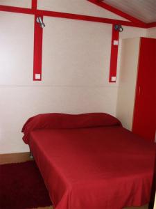 Parque de Campismo Orbitur Montargil في مونتارجيل: غرفة نوم بسرير احمر مع بطانية حمراء