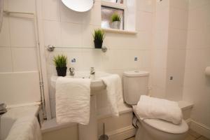 a bathroom with a toilet and a sink with towels at StayZo Penthouse Accommodation 1- Premier Lodge in Southampton