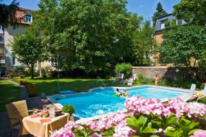 a swimming pool with people in a yard with pink flowers at Hotel-Pension Berger in Heidelberg