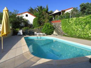 a swimming pool with an umbrella and a house at Quinta da quebrada in Santana