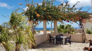 a patio with tables and chairs and a view of the beach at Casa do Cisne in Porto Santo