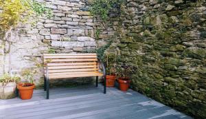 um banco de madeira sentado em frente a uma parede de pedra em Parliament Street Town House em Ennistymon