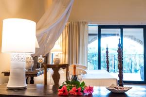 a bedroom with a bed and a table with a lamp at Hotel Costa dei Fiori in Santa Margherita di Pula