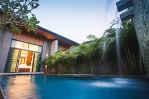 a swimming pool in front of a building with a fountain at Two Villas Holiday Phuket: Onyx Style Nai Harn Beach in Nai Harn Beach