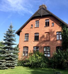 a large brick building with a tree in front of it at Stara Szkoła w Harszu in Pozezdrze