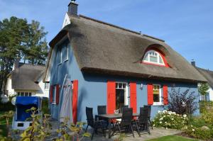 a blue and red house with a table and chairs at Ferienhaus Vier Jahreszeiten in Glowe