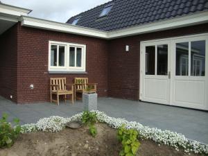 een stenen huis met een witte garagedeur en stoelen bij B&B Hanenberg in Oijen