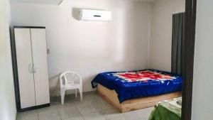 a small bedroom with a bed and a chair at Casa Para Locação in Piratuba